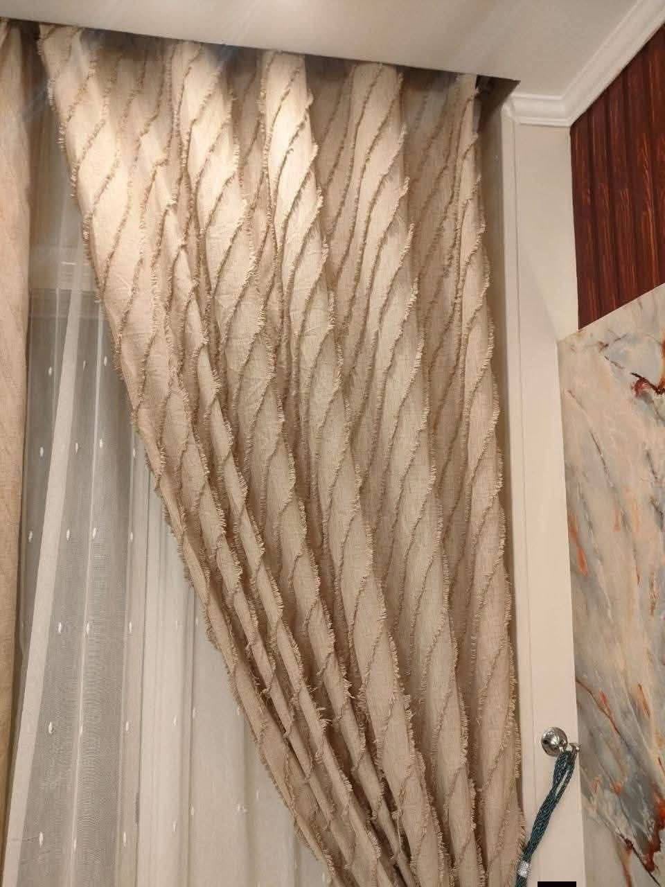 Close-up of textured beige curtain with white sheers in a room setting.